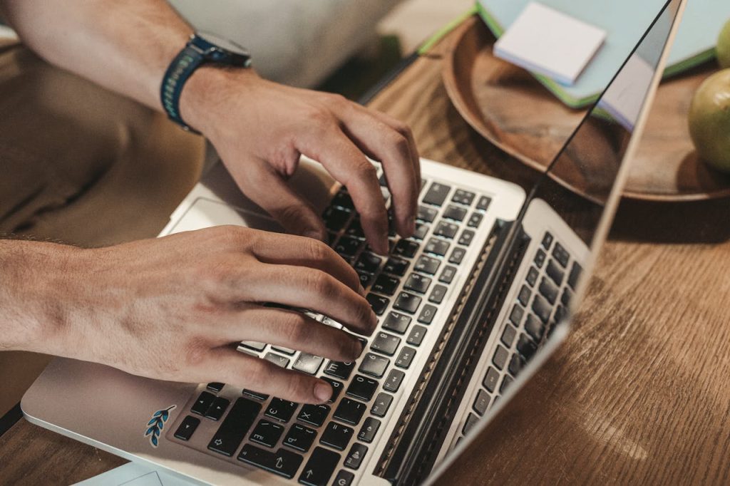 Close-up of hands typing on a laptop, capturing a productive indoor workspace vibe.